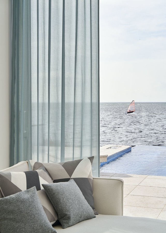 Modra prosojna zavesa po meri v sodobni dnevni sobi z razgledom na morje